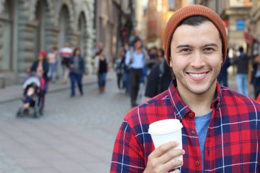 Eski şehir caddesinde tek kullanımlık kahvesi olan yakışıklı bir gencin yakın plan portresi.
