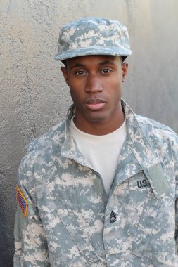 Gri duvarın önündeki yakışıklı Afro-Amerikan askerinin yakın plan portresi.