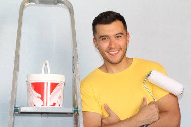 Neşeli etnik erkek evinde bir duvar boyamak üzere.