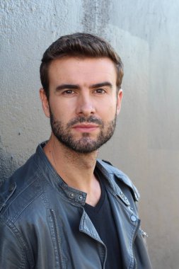 Duvarın önündeki yakışıklı sakallı adamın yakın plan portresi.