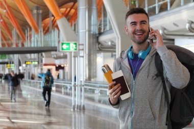Genç bir adam havaalanından telefon alıyor.