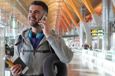 Genç bir adam havaalanından telefon alıyor.