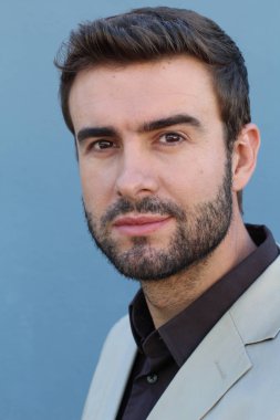 Duvarın önündeki yakışıklı sakallı adamın yakın plan portresi.