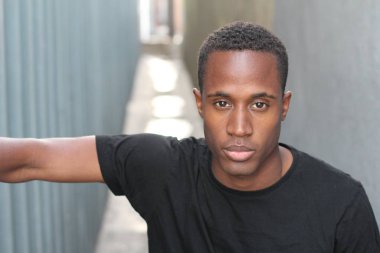 Sokakta siyah tişörtlü yakışıklı Afro-Amerikan adamın yakın plan portresi.