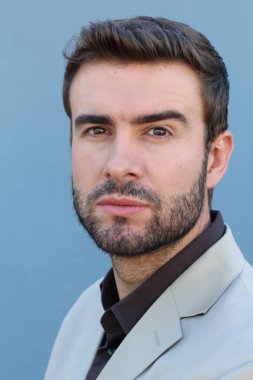 Duvarın önündeki yakışıklı sakallı adamın yakın plan portresi.