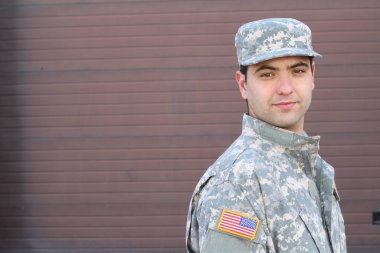 close-up portrait of handsome young soldier in front of brown wall