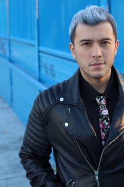 Yakından çekilen, renkli saçlı, şık giyimli yakışıklı bir genç adam.