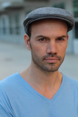 Yakından bakınca şık giyinmiş ve şapkalı yakışıklı bir genç adam var.