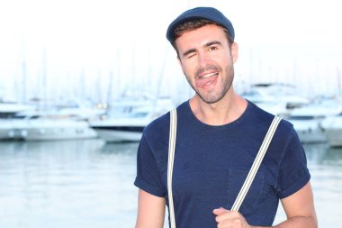 Gün batımında yatların önünde şık giyinmiş yakışıklı bir gencin yakın plan portresi. 