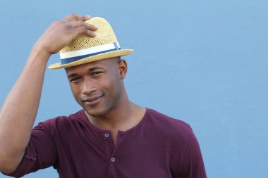 Mavi duvarın önünde şapkalı yakışıklı Afro-Amerikan bir adamın yakın plan portresi.