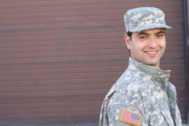 close-up portrait of handsome young soldier in front of brown wall