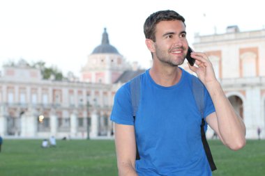 Eski Avrupa şehrinin caddesinde telefonla konuşan yakışıklı genç adamın yakın plan portresi.