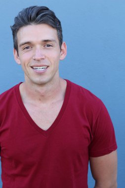 Mavi duvarın önündeki yakışıklı genç adamın yakın plan portresi.