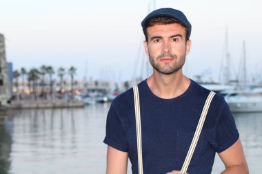 Gün batımında yatların önünde şık giyinmiş yakışıklı bir gencin yakın plan portresi. 