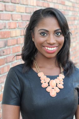 Tuğla duvar arkasında kendine güvenen zarif, genç, siyah bir kadın.