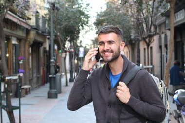 Avrupa 'nın caddesinde günlük kıyafetlerle konuşan yakışıklı genç adamın yakın plan portresi.