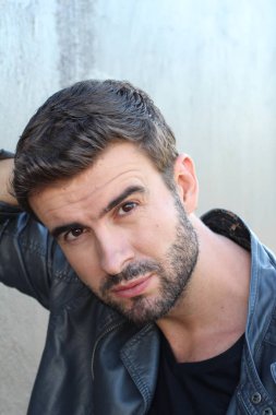 Duvarın önündeki yakışıklı sakallı adamın yakın plan portresi.
