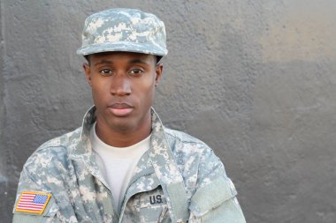 Gri duvarın önündeki yakışıklı Afro-Amerikan askerinin yakın plan portresi.