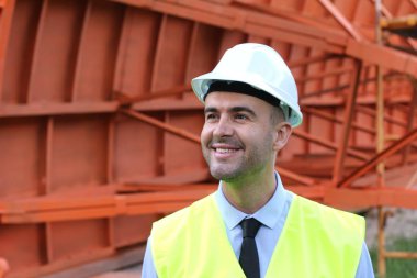 İnşaat alanında koruyucu yelek giymiş yakışıklı bir mimarın yakın plan portresi.