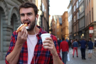 Etnik erkek dışarıda sosisli yiyor.