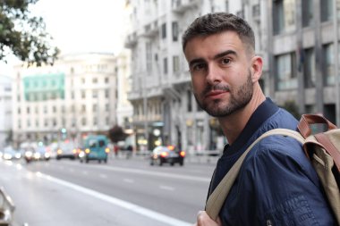 Şehir caddesinde sıradan kıyafetler giymiş yakışıklı bir gencin yakın plan portresi.