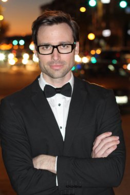 smokinli ve papyonlu yakışıklı bir delikanlının akşam vakti şehir caddesinde yakın plan fotoğrafı.