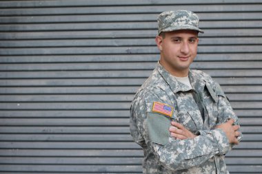 Gri duvarın önündeki yakışıklı genç askerin yakın plan portresi.
