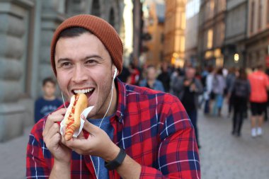 Etnik erkek sosisli sandviç yiyor.