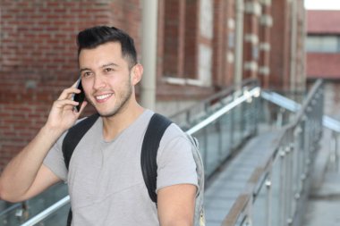 Sokakta telefonla konuşan, günlük kıyafetler içindeki yakışıklı genç adamın yakın plan portresi.