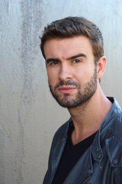 Duvarın önündeki yakışıklı sakallı adamın yakın plan portresi.