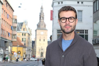 Eski Avrupa şehrinin sokaklarında günlük giysiler içinde yakışıklı bir gencin yakın plan portresi.