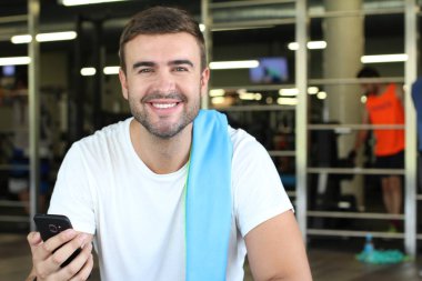 Spor salonunda oturan motive bir adam.