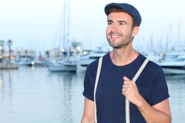 Gün batımında yatların önünde şık giyinmiş yakışıklı bir gencin yakın plan portresi. 