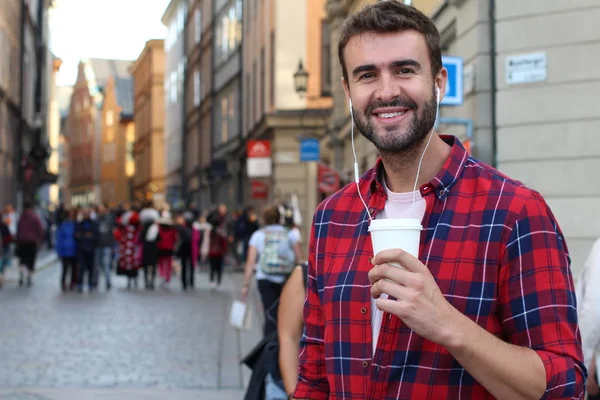 Sokakta elinde kağıt kahve olan yakışıklı bir gencin yakın plan portresi.