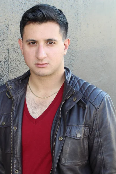 close-up portrait of handsome young man in leather jacket in front of concrete wall