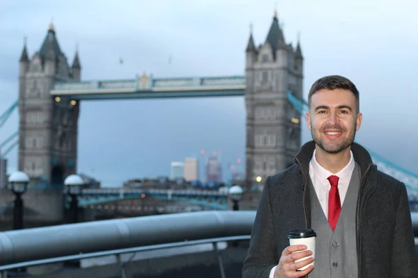 英国ロンドンのタワーブリッジの前でコーヒーを紙コップでハンサムな若いビジネスマンのクローズアップ肖像画 — ストック写真