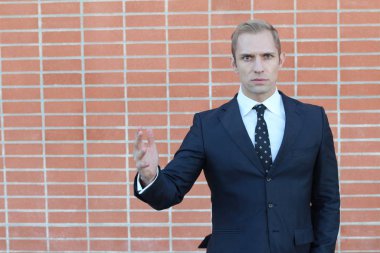 Yakışıklı, yetişkin bir iş adamının sokakta tuğla duvarın önünde yakın plan çekimi.