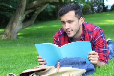 Parktaki çimlerde çalışan yakışıklı genç öğrencinin yakın plan portresi.