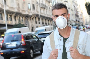 Sokakta tıbbi güvenlik maskesi takmış yakışıklı genç adamın yakın plan portresi.