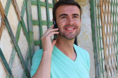 close-up portrait of handsome young man talking by phone on street