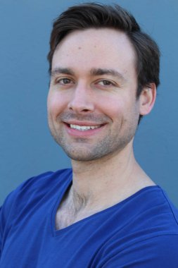 Mavi duvarın önünde sıradan giyinmiş yakışıklı bir gencin yakın plan portresi.