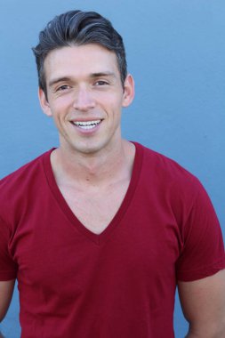 Mavi duvarın önündeki yakışıklı genç adamın yakın plan portresi.