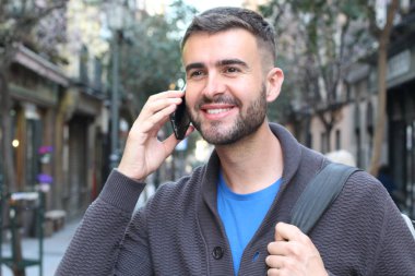 Avrupa 'nın caddesinde günlük kıyafetlerle konuşan yakışıklı genç adamın yakın plan portresi.