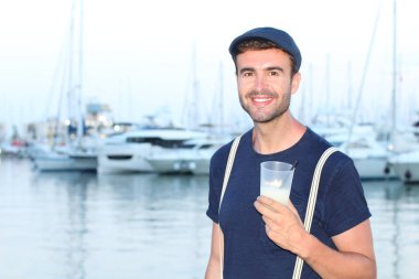 Gün batımında yatların önünde şık giyinmiş yakışıklı bir gencin yakın plan portresi. 