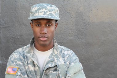 Gri duvarın önündeki yakışıklı Afro-Amerikan askerinin yakın plan portresi.