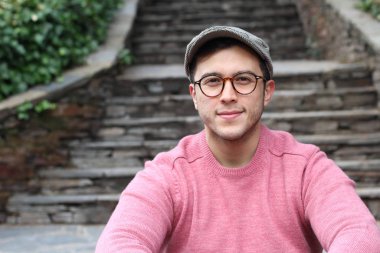 Şehir caddesinde sıradan kıyafetler giymiş yakışıklı bir gencin yakın plan portresi.