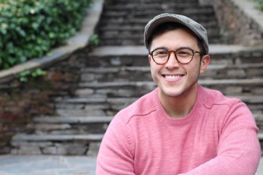 Şehir caddesinde sıradan kıyafetler giymiş yakışıklı bir gencin yakın plan portresi.