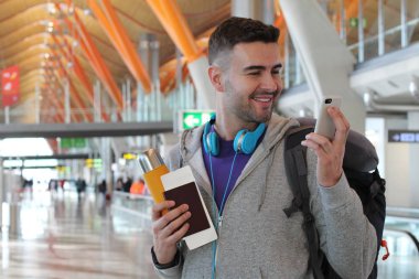 Genç bir adam havaalanından telefon alıyor.