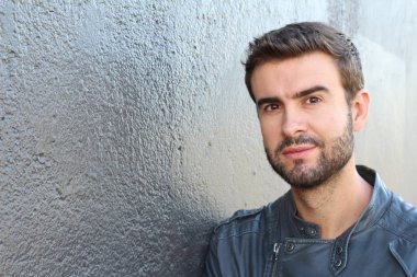 Duvarın önündeki yakışıklı sakallı adamın yakın plan portresi.