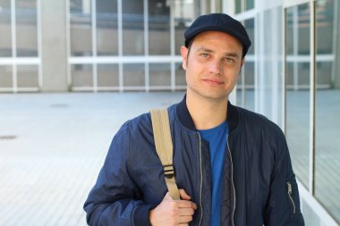 Yakından çekilmiş, sıradan kıyafetler giymiş ve şapkalı yakışıklı genç bir adam portresi.